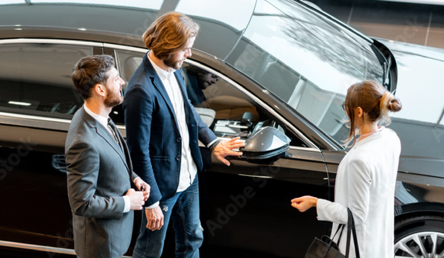 A salesman in a showroom showing a couple a car
