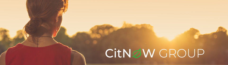 Woman watching sunset over tress, with CitNOW Group logo in corner